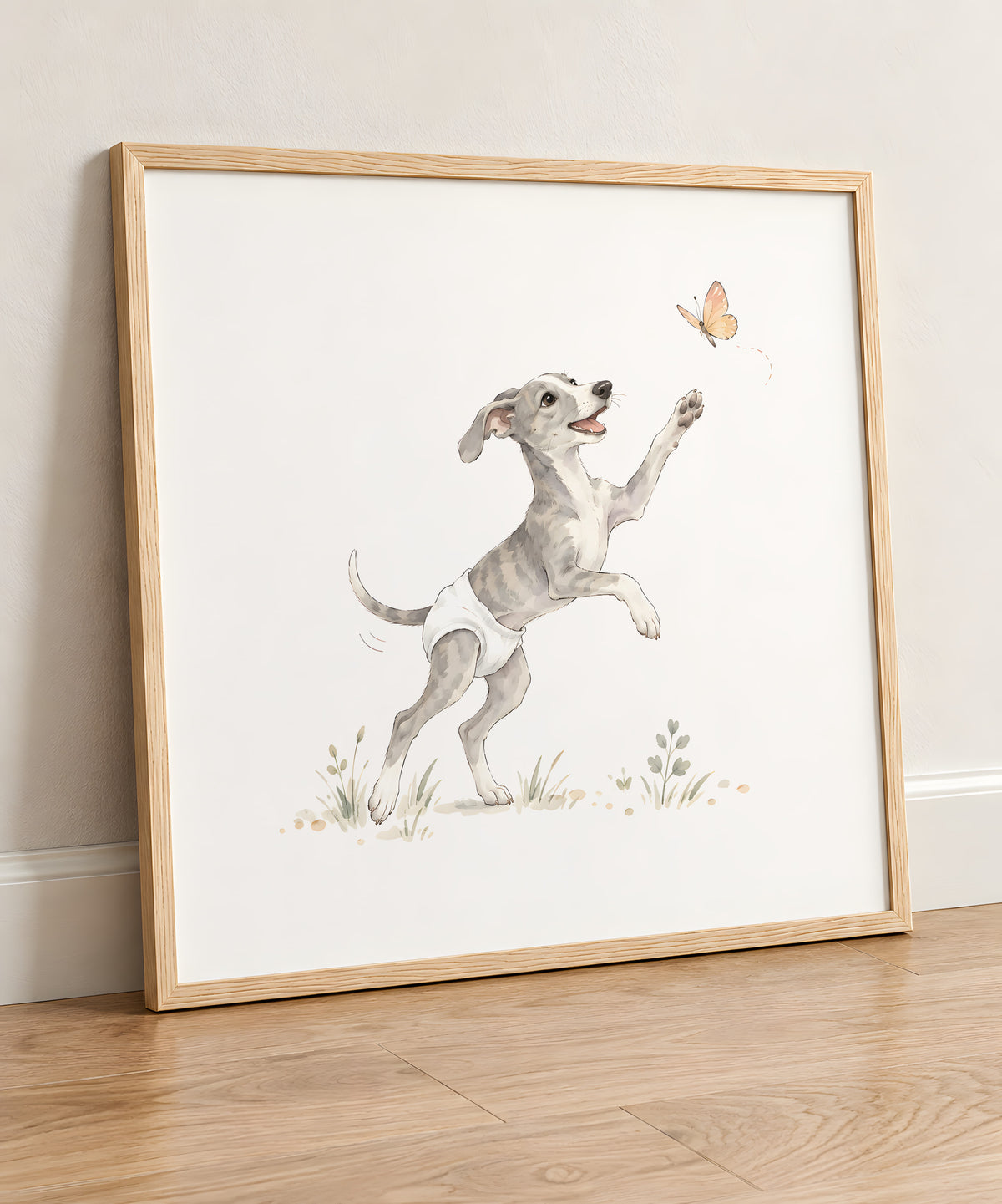 Bébé lévrier en couche blanche tend la patte vers un papillon : cadre bois clair, 50 × 50 cm, en situation