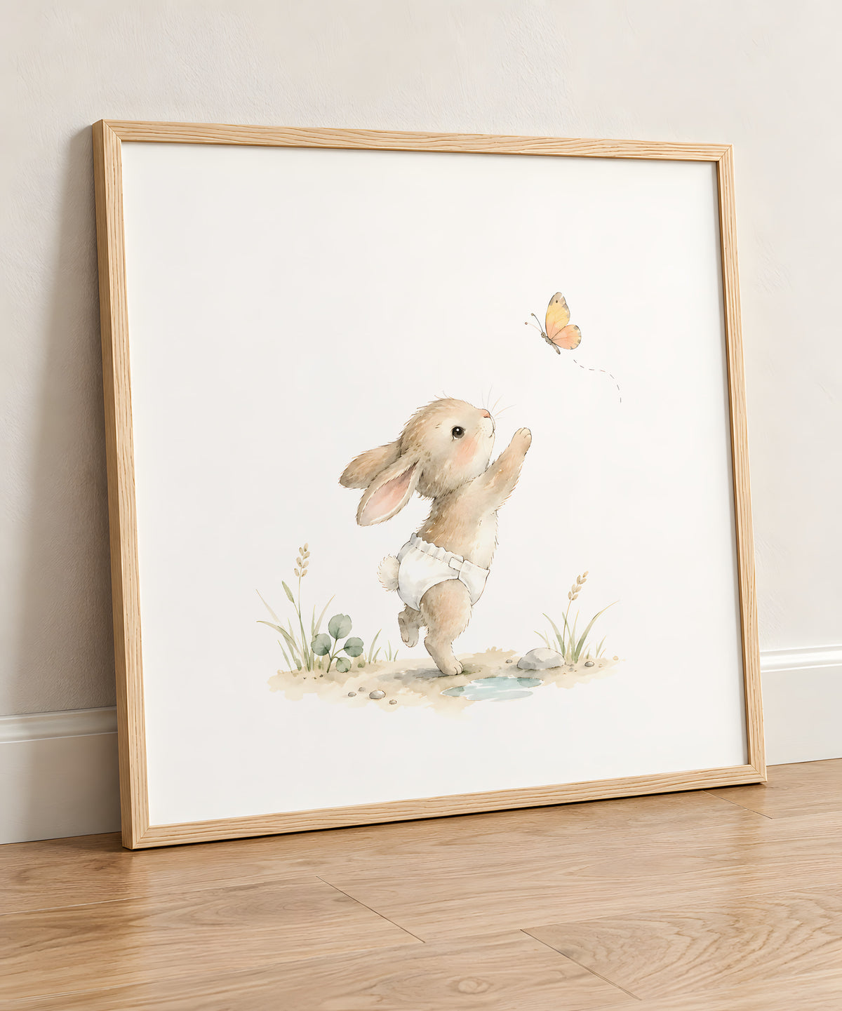 Bébé lapin en couche blanche tend les pattes vers un papillon : cadre bois clair, 50 × 50 cm, en situation