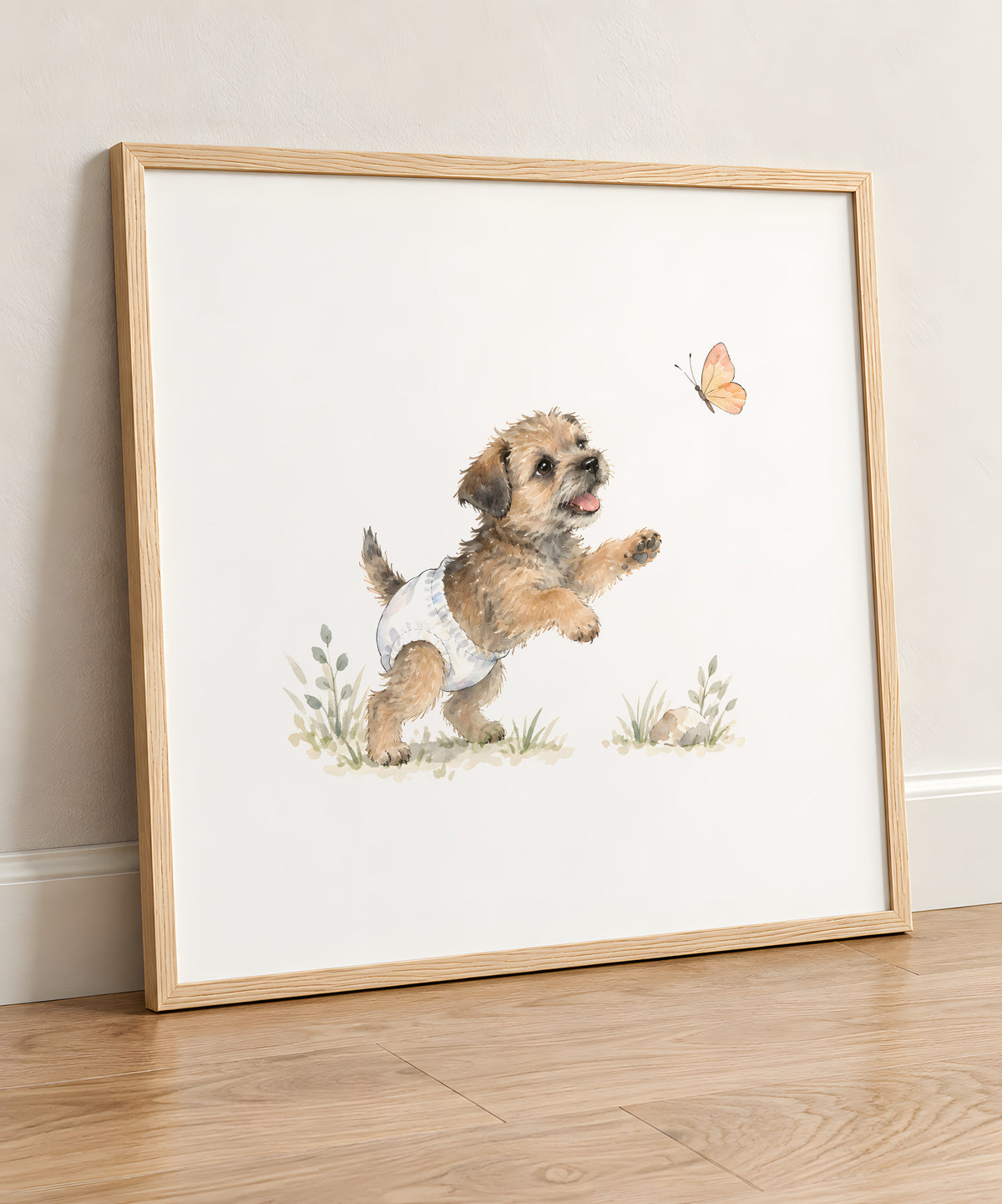 Bébé border terrier en couche blanche essaie d’attraper un papillon : cadre bois clair, 50 × 50 cm, en situation