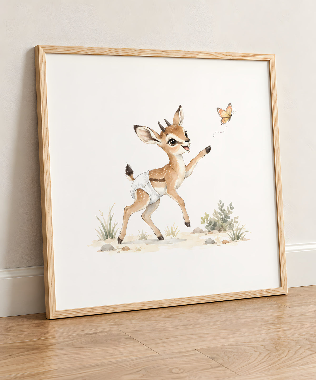 Bébé gazelle en couche blanche essaie d’attraper un papillon : cadre bois clair, 50 × 50 cm, en situation