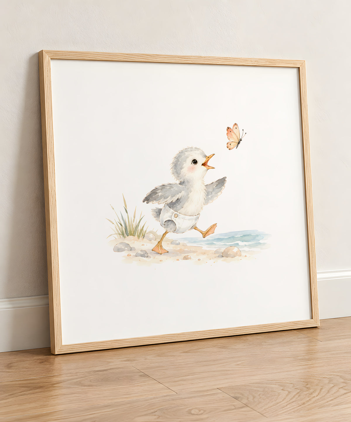Bébé mouette en couche blanche à la poursuite d’un papillon : cadre bois clair, 50 × 50 cm, en situation