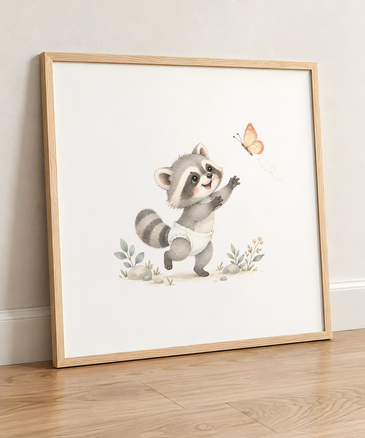 Bébé raton laveur en couche blanche attrape un papillon entre ses pattes : cadre bois clair, 50 × 50 cm, en situation