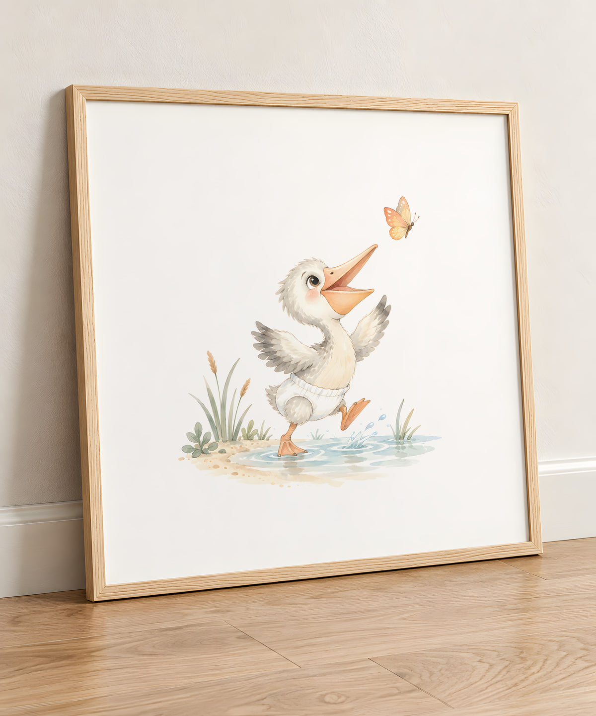 Bébé pélican en couche blanche tente d’attraper un papillon au bord de l’eau : cadre bois clair, 50 × 50 cm, en situation