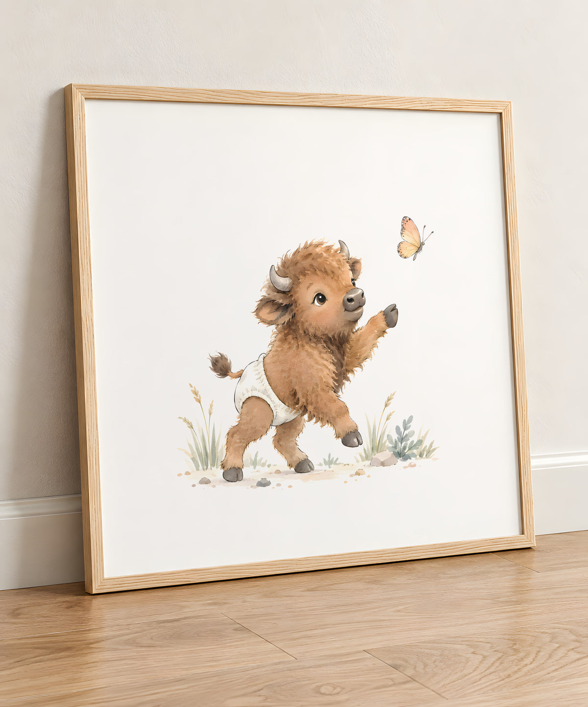 Bébé bison en couche blanche essaie d’attraper un papillon : cadre bois clair, 50 × 50 cm, en situation