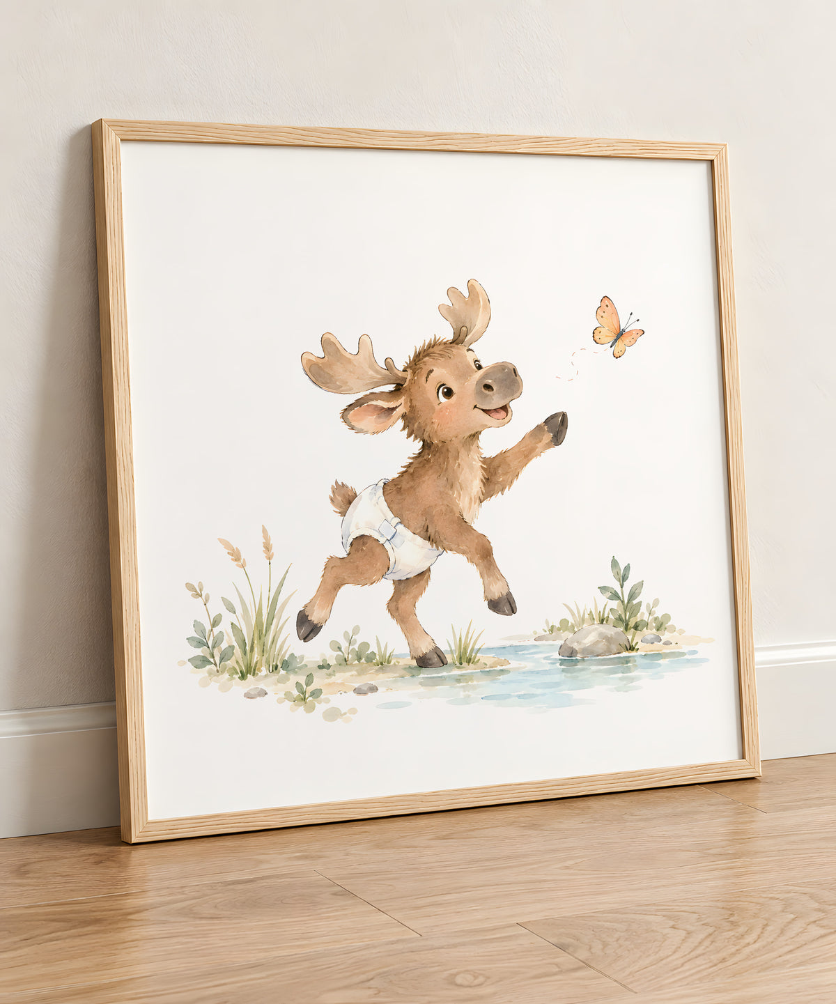 Bébé élan en couche blanche essaie d’attraper un papillon : cadre bois clair, 50 × 50 cm, en situation