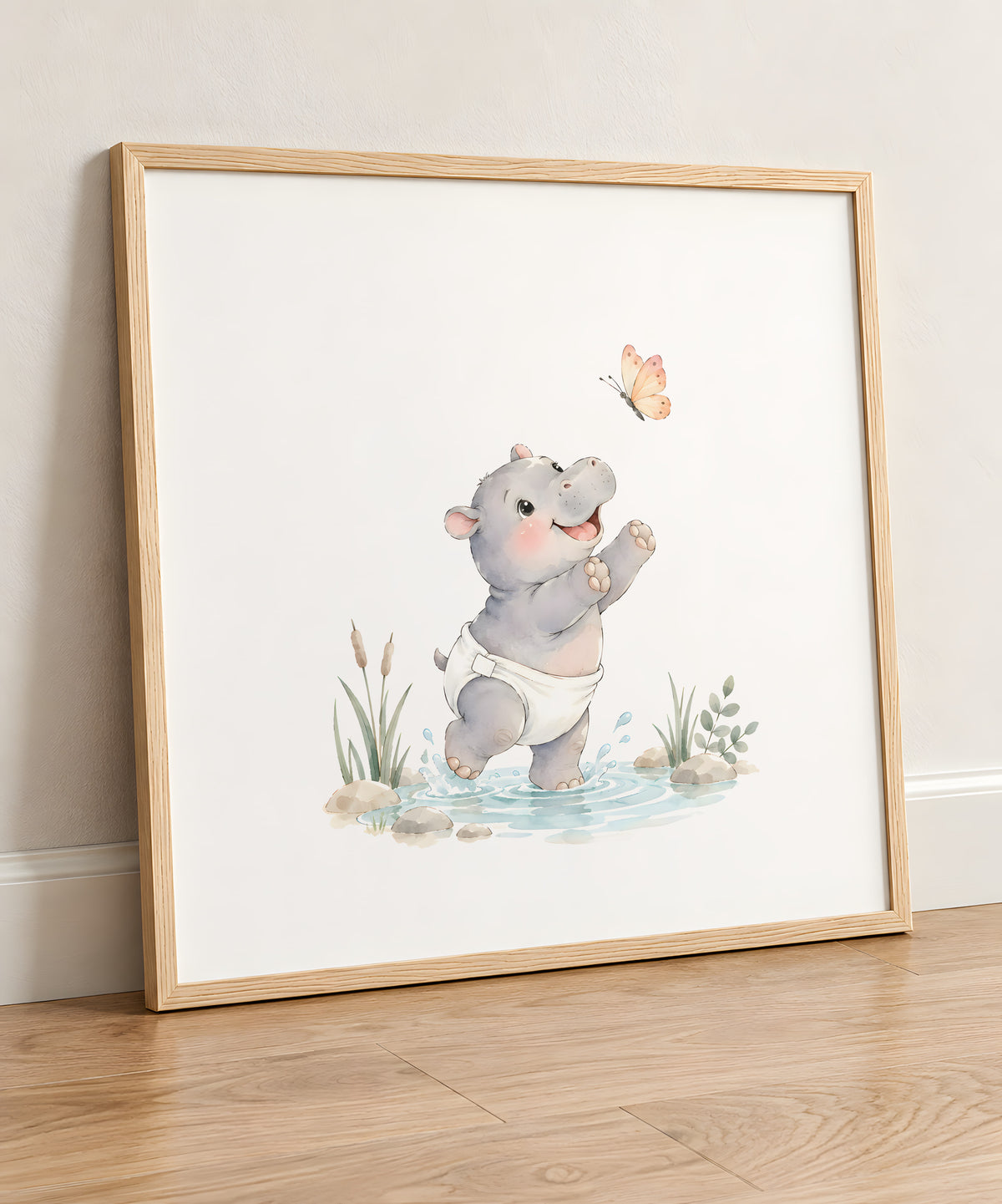 Bébé hippopotame en couche blanche chasse un papillon au bord de l’eau : cadre bois clair, 50 × 50 cm, en situation